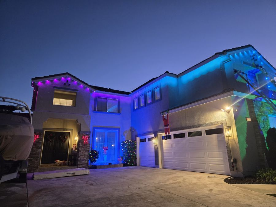 Two-story home glowing blue and purple at dusk